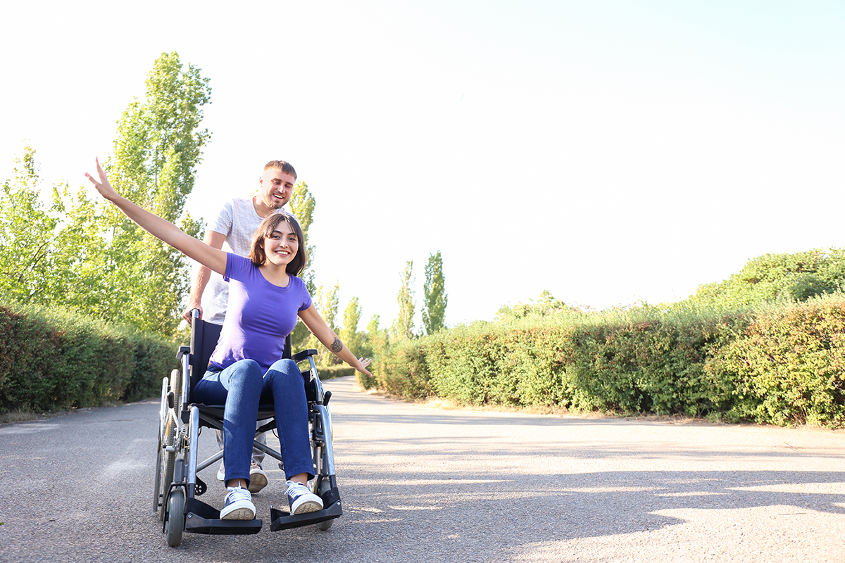 Chica en silla de ruedas y su acompañante en un parque