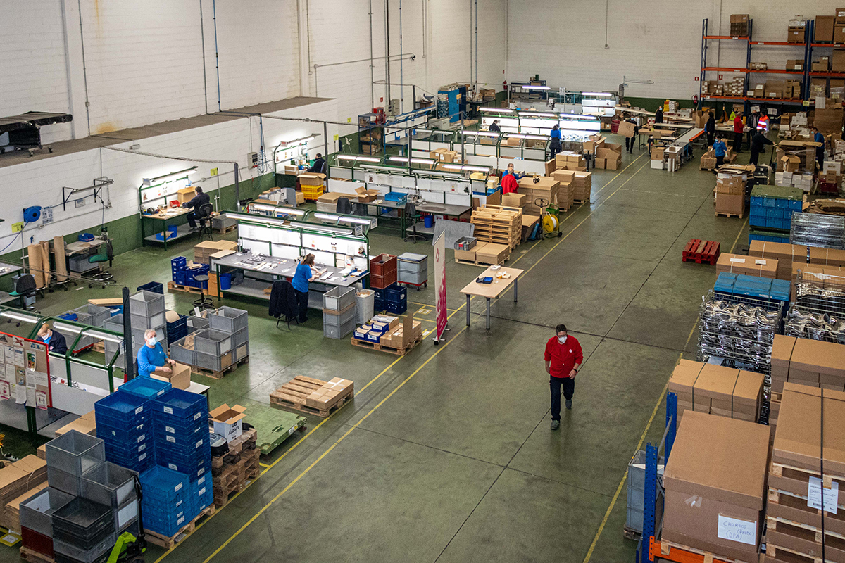 Imagen vista desde arriba de un taller con maquinaria, cajas y una persona caminando por un pasillo central