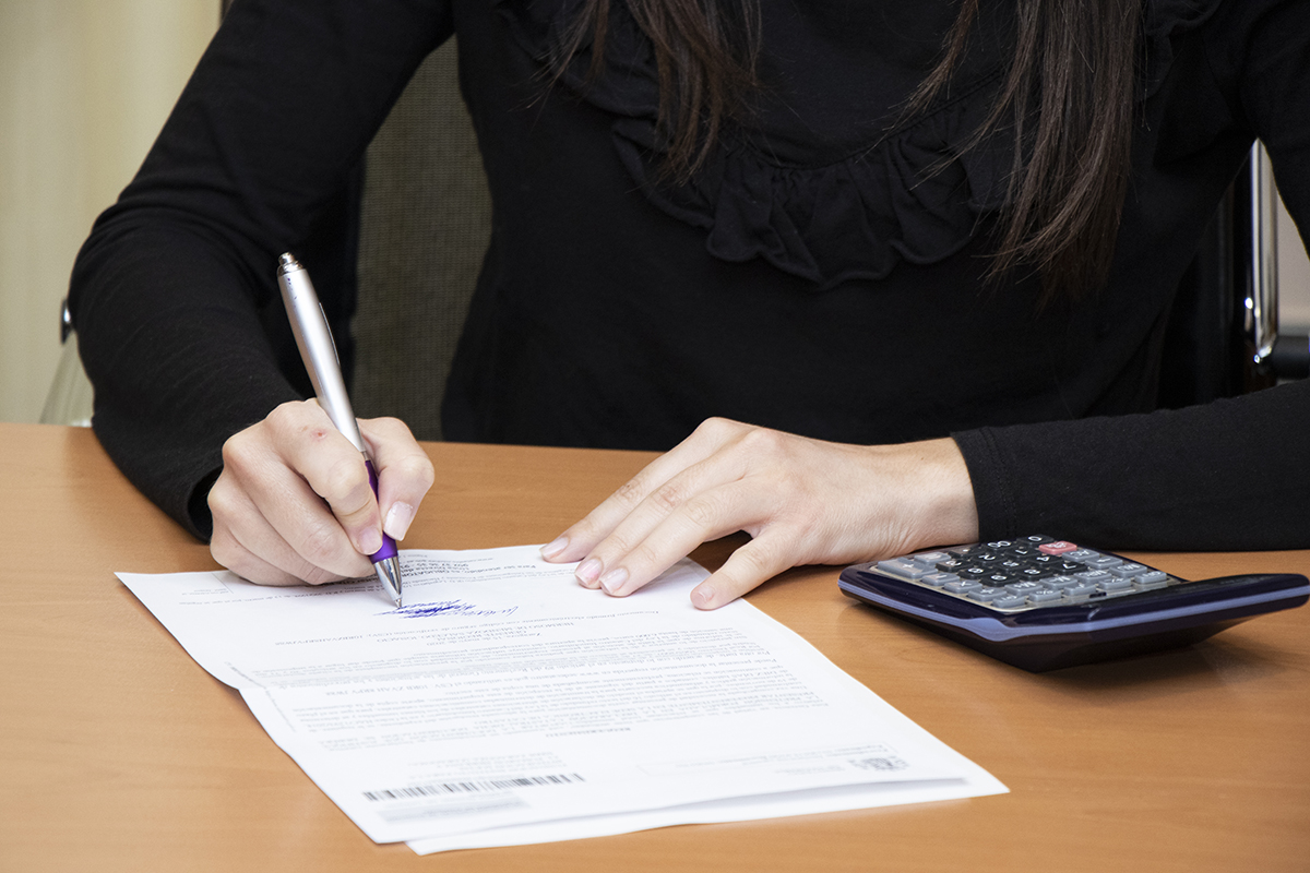 Manos de una mujer rellenando un documento con una calculadora