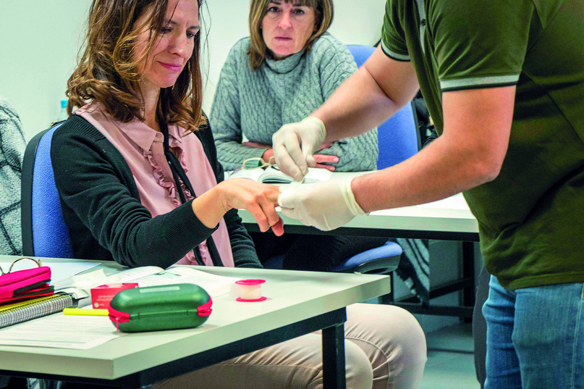 Mujer aprendiendo a vendar una herida en un aula