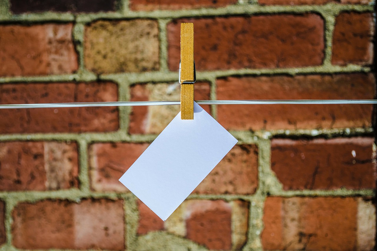 Un papel en blanco colgado con una pinza frente a una pared