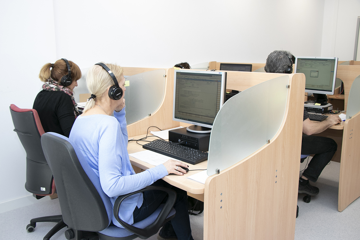 Sala de atención telefónica con varias personas delante de un ordenador y auriculares
