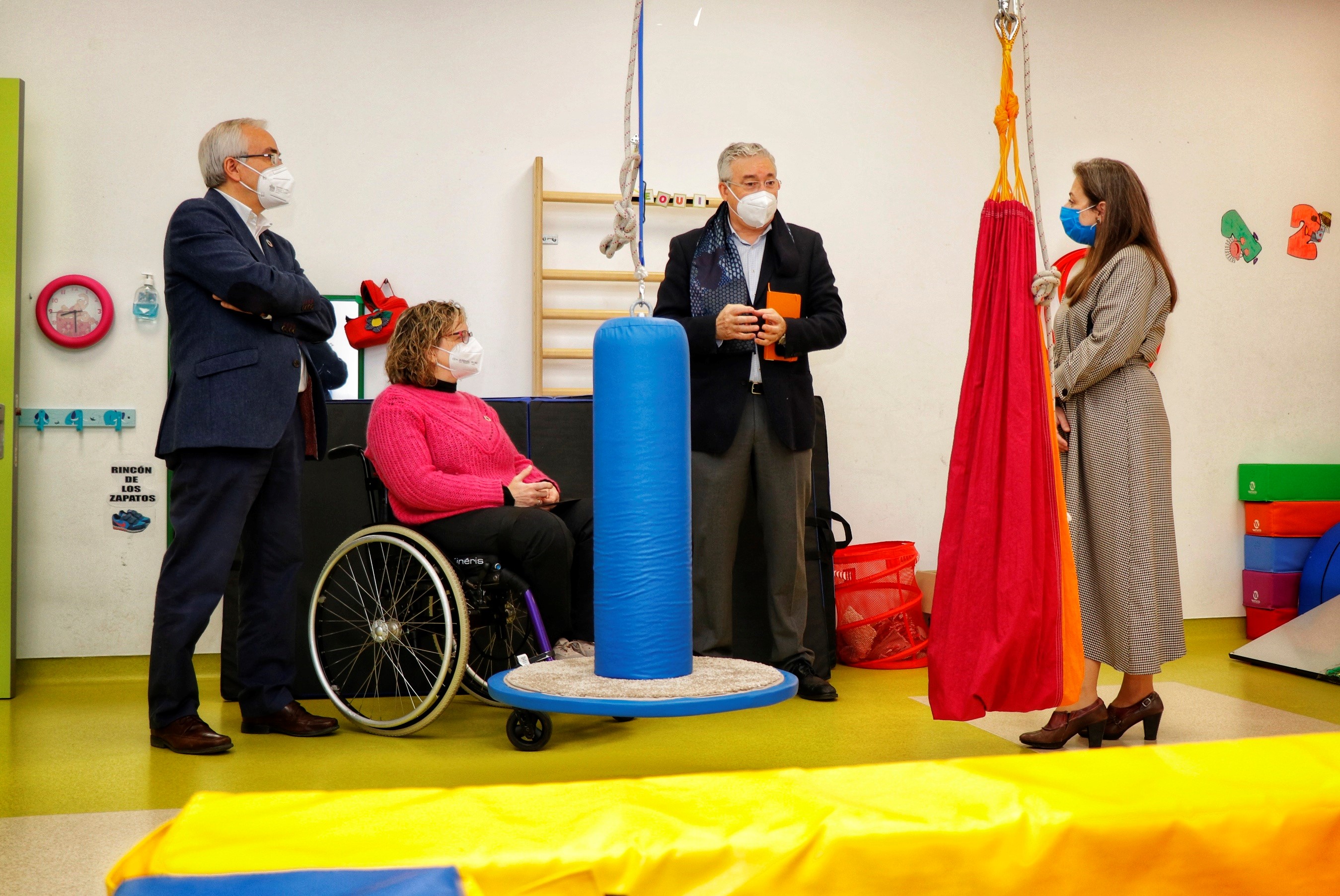 Sala de desarrollo infantil colorida y con diferentes elementos con varias personas visitandolo