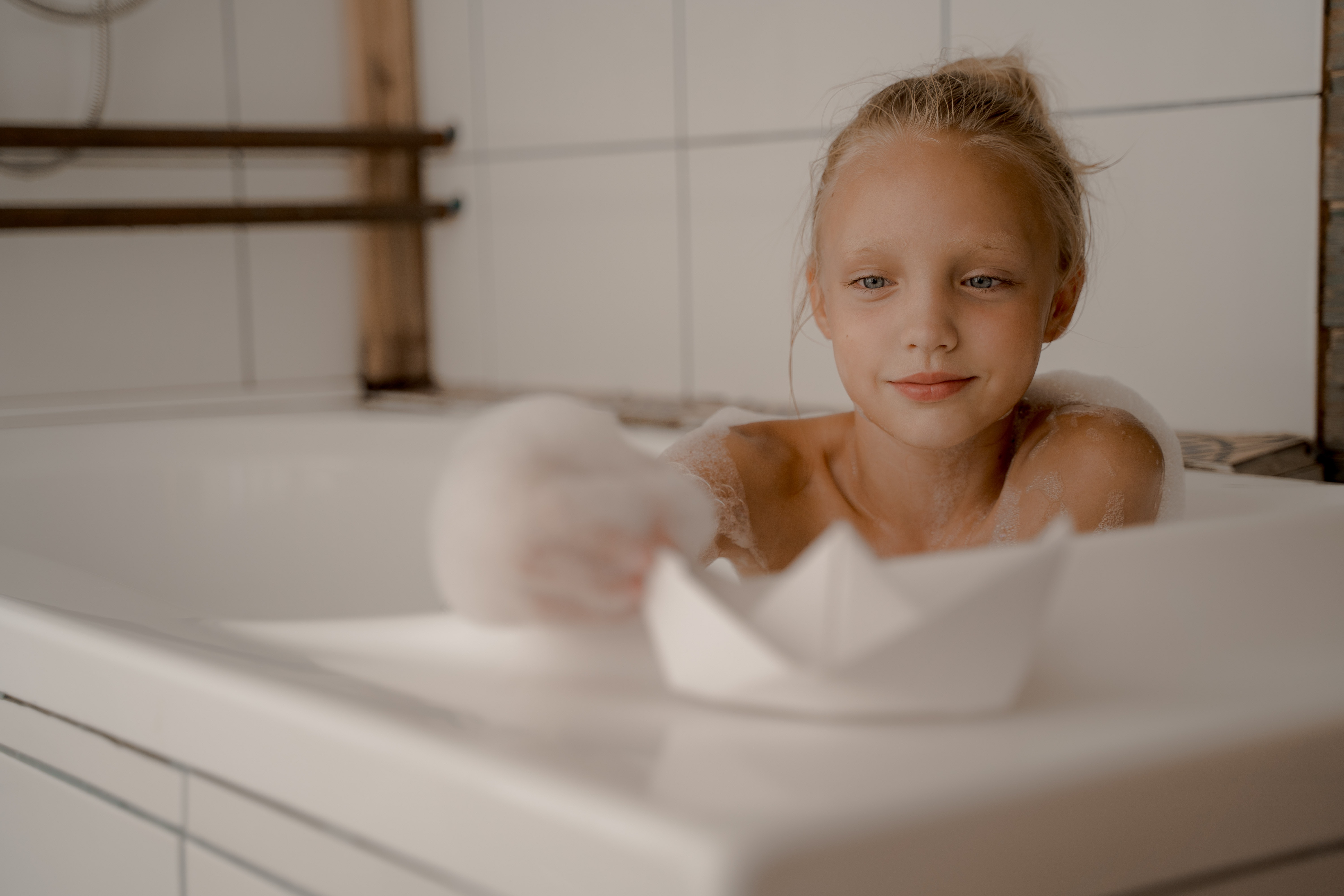 Niña en la bañera con barco de papel