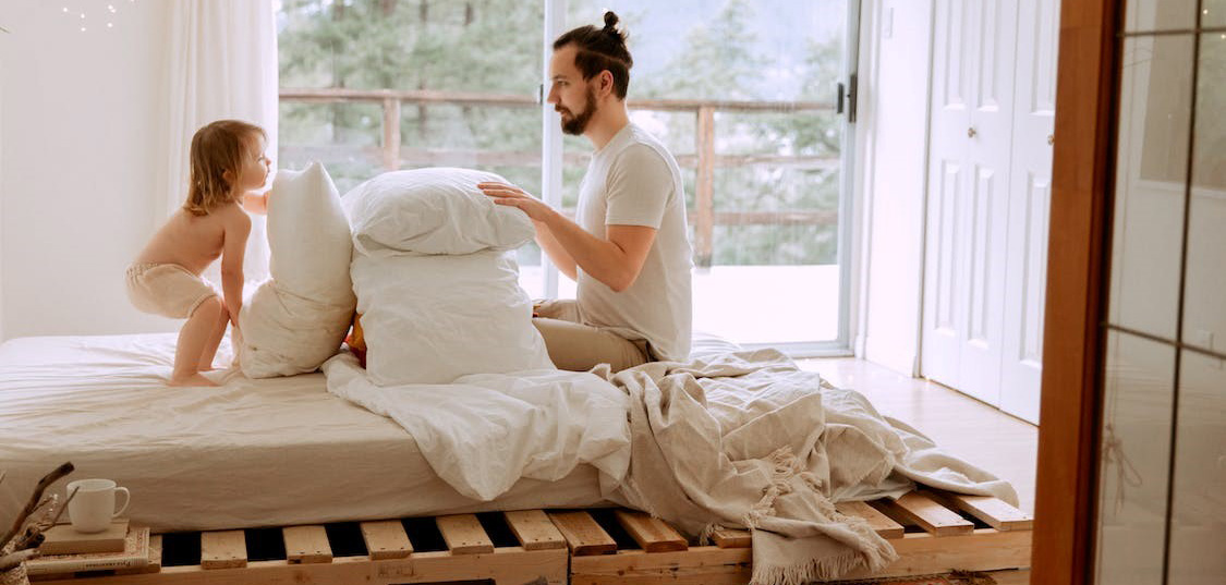Una madre y su padre jugando con almohadas en casa