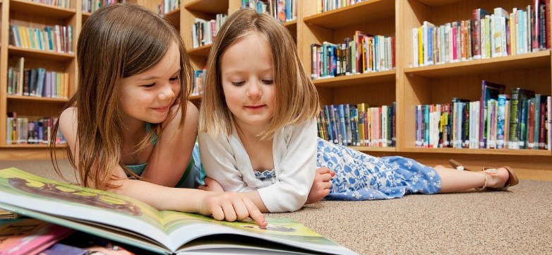 Dos niñas leyendo un cuento en el suelo