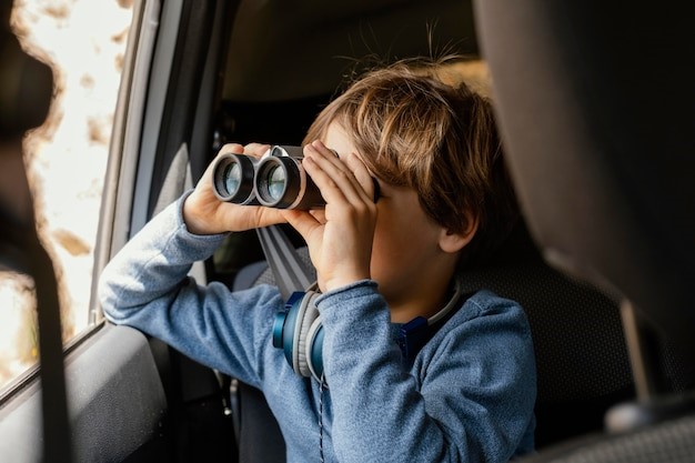 Niño mirando a través de prismáticos en el coche