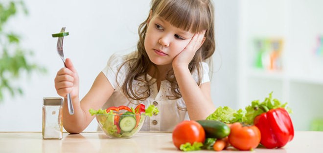 Niña mirando comida con desgana