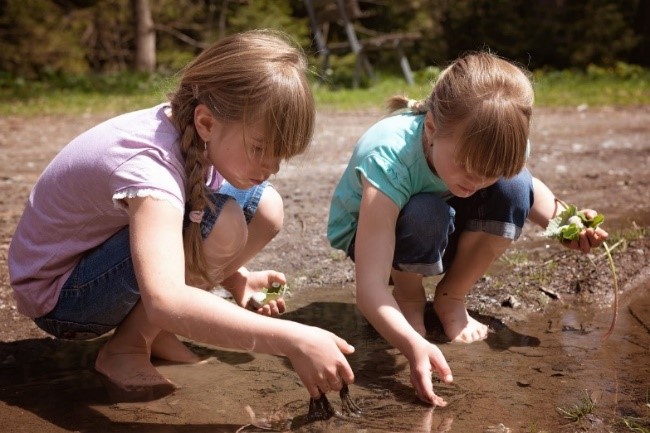 Un niño y una niña juegan con un charco