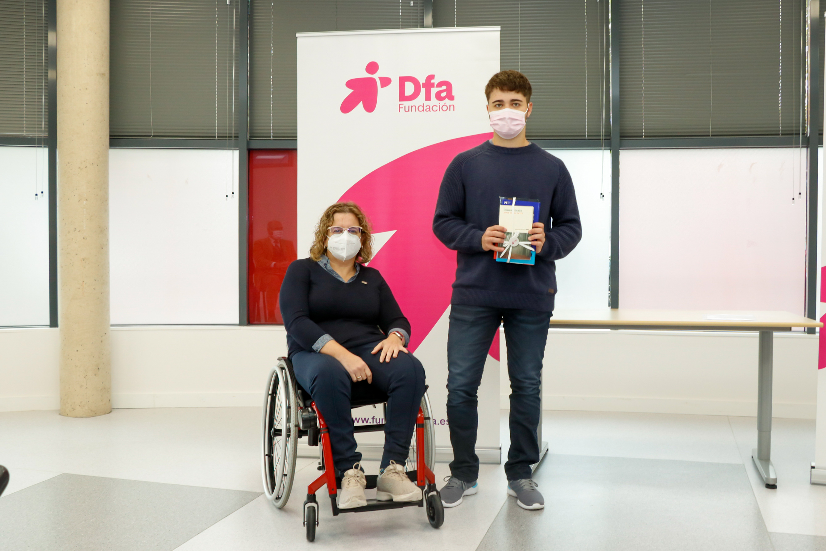 Un joven posa en una entrega de premios junto a una mujer en silla de ruedas