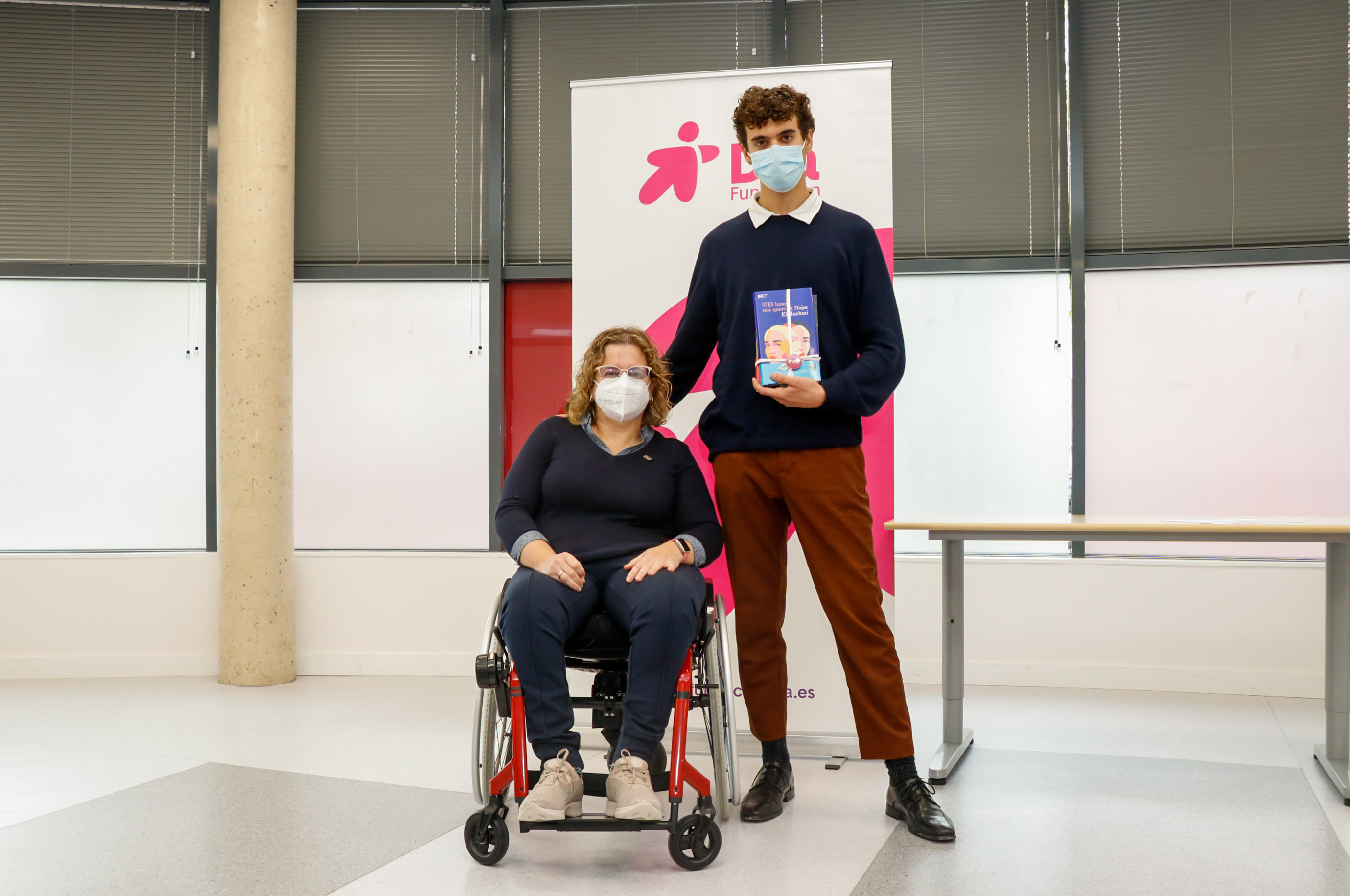 Un joven posa en una entrega de premios junto a una mujer en silla de ruedas