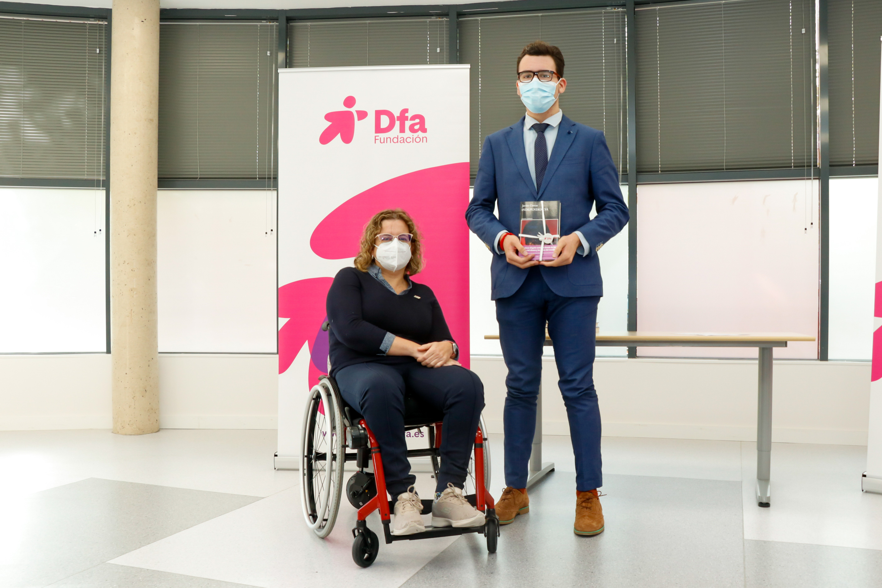 Un joven posa en una entrega de premios junto a una mujer en silla de ruedas
