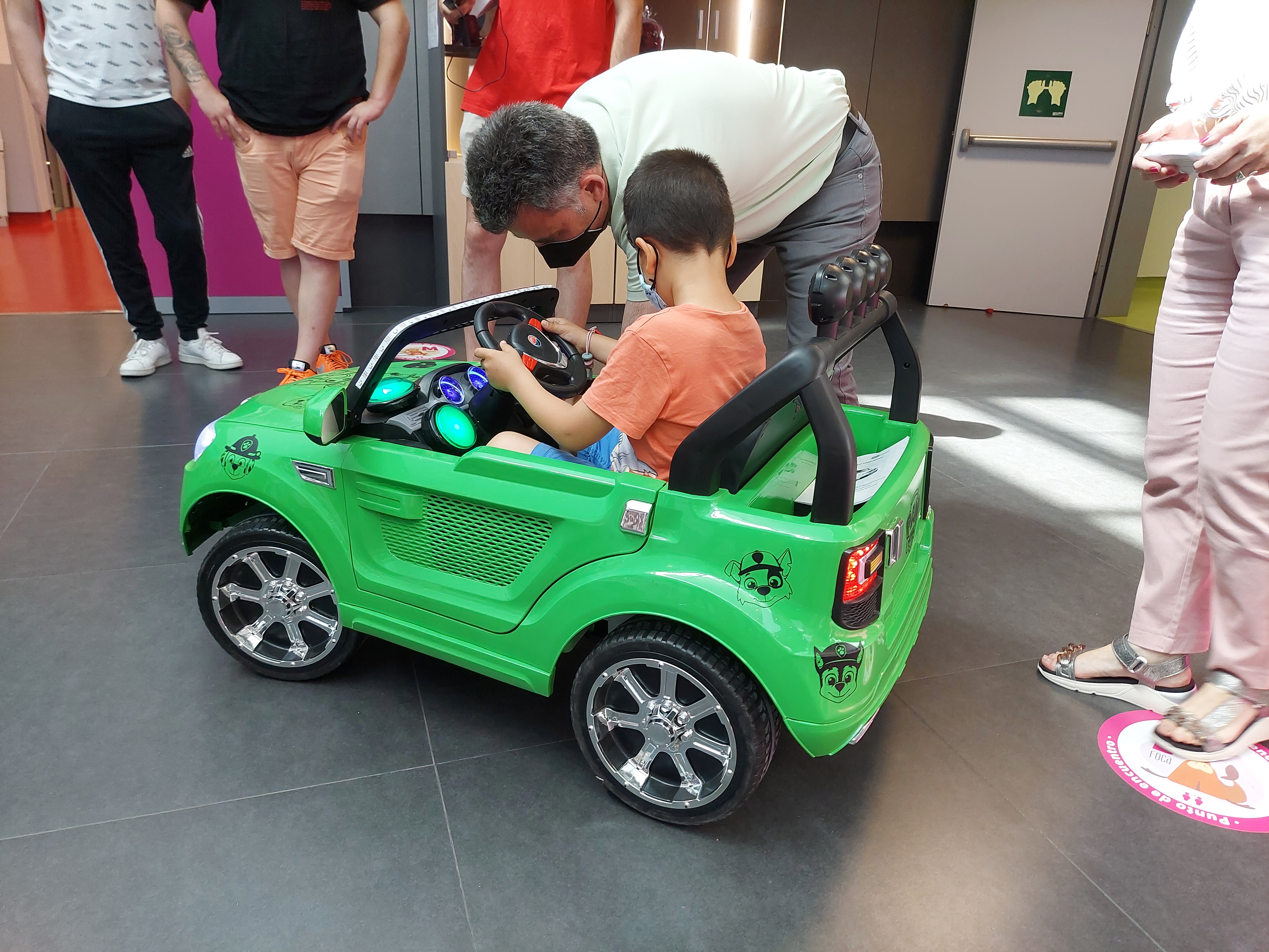 Un niño utilizando un coche eléctrico infantil verde