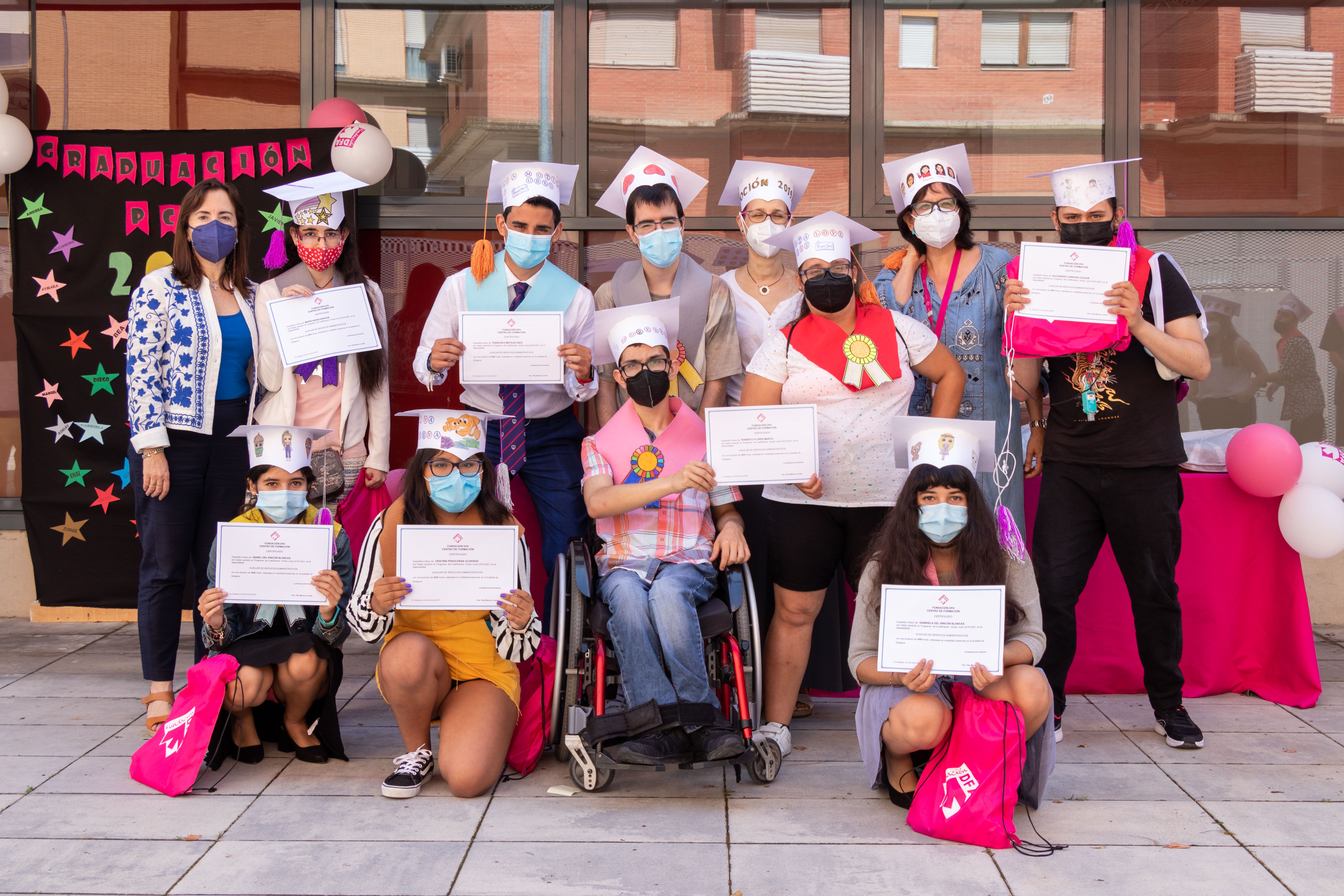 Foto de familia del alumnado de los PCI con birretes junto a sus profesoras