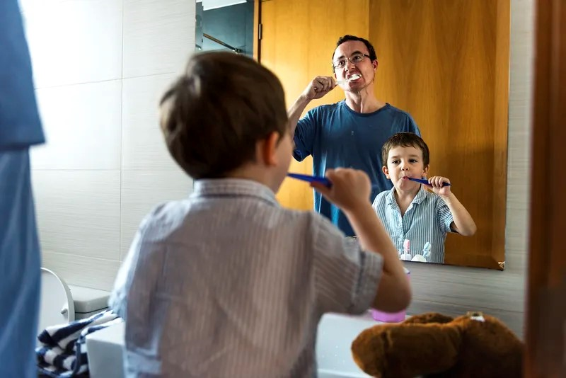Un padre y un hijo se lavan los dientes