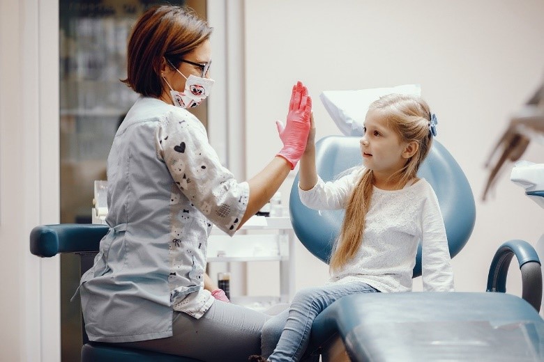 Un niño una dentista chocan las manos