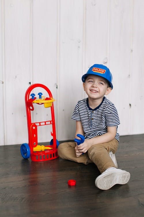 Un niño sonríe junto a un juguete