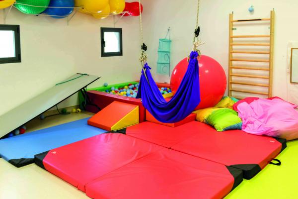 Sala de Atención temprana muy colorida con material adaptado, colchonetas, pelotas de goma, hamaca...