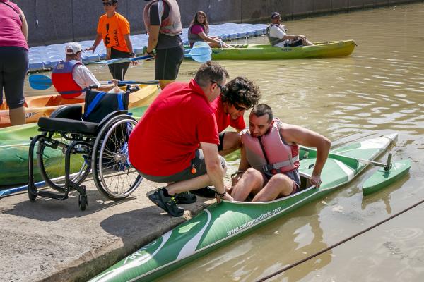 Joven con discapacidad dentro de una canoa en un río ayudado por un técnico