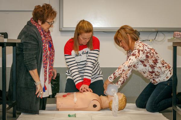 Tres mujeres en un taller sanitario aprendiendo a hacer un masaje de reanimación cardiopulmonar a un muñeco