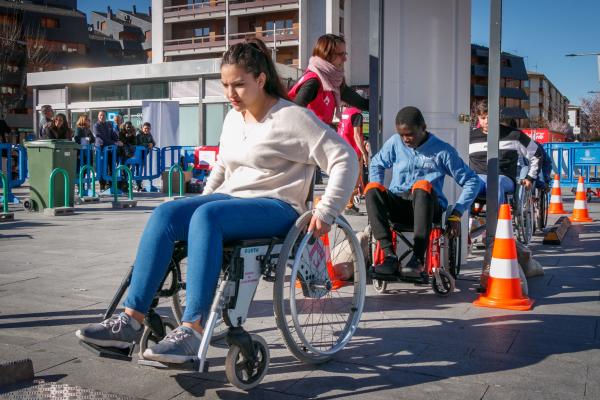 Jóvenes en sillas de ruedas en una yincana de obstáculos atravesando una puerta