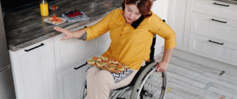 Mujer en silla de ruedas hablando por teléfono en una cocina