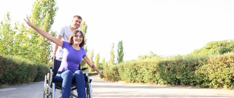 Chica en silla de ruedas y su acompañante en un parque
