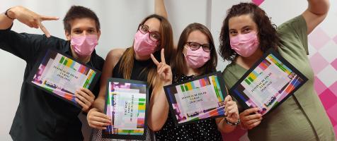 Un chico y tres chicas posan felices ante la cámara con tarjetas del Festival de Fin de Curso