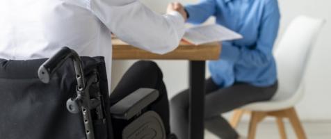 Mujer habla en una mesa con un hombre en silla de ruedas