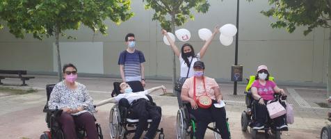 Cuatro usuarios y usuarias de silla de ruedas con dos voluntarios de paseo
