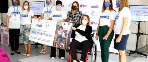 Varias personas con camisetas de Carrefour entregan un cheque gigante a dos mujeres