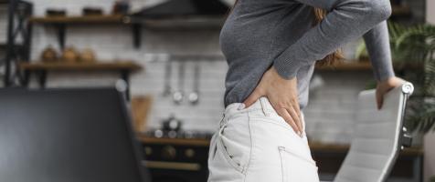 Chica se lleva la mano a la espalda por dolor