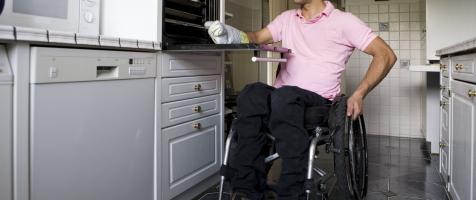 Un usuario de silla de ruedas en la cocina de su casa
