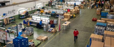 La imagen muestra una nave industrial perteneciente a un centro especial de empleo de Fundación Dfa, con diferentes trabajadores y trabajadoras en sus puestos