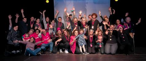 La imagen muestra a parte del equipo de Voluntariado de Fundación Dfa sobre el escenario del salón de actos del Centro de Convivencia para Mayores Laín Entralgo