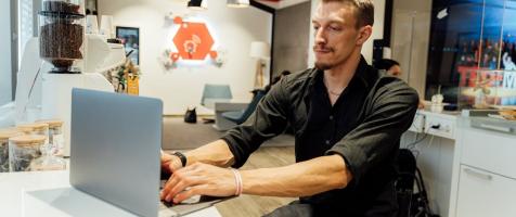 Un hombre en silla de ruedas trabaja con un ordenador
