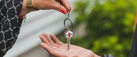 La imagen muestra una mano depositando una llave en la palma de otra mano