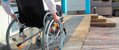 Persona en silla de ruedas subiendo una rampa