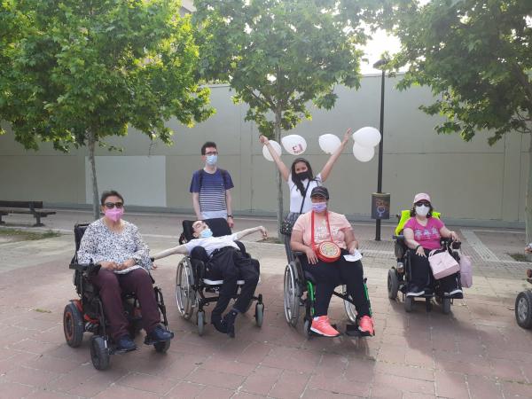 Cuatro usuarios y usuarias de silla de ruedas con dos voluntarios de paseo