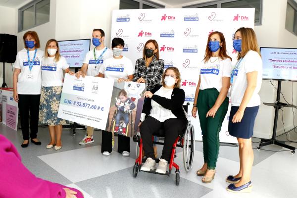 Varias personas con camisetas de Carrefour entregan un cheque gigante a dos mujeres