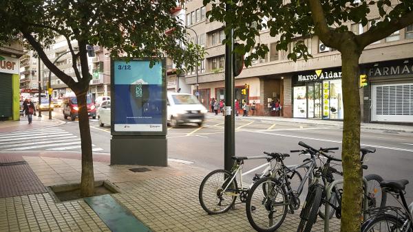 Una calle con un mupi con el cartel de la campaña del 3 de diciembre