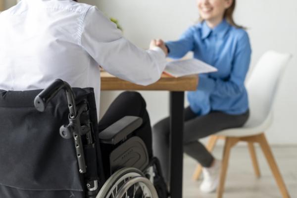 Un usuario de silla de ruedas es atendido por una mujer en una oficina