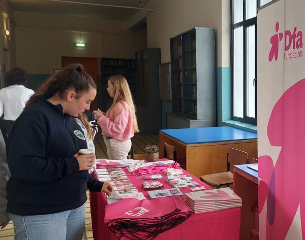 Una chica observa los folletos de voluntariado en el puesto de Dfa