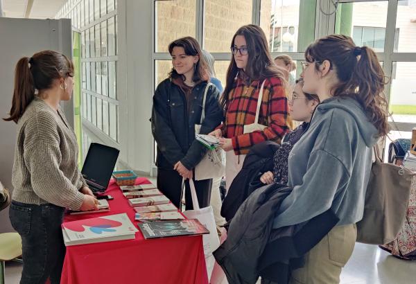 Una trabajadora de Dfa ofrece información a varias alumnas en el stand