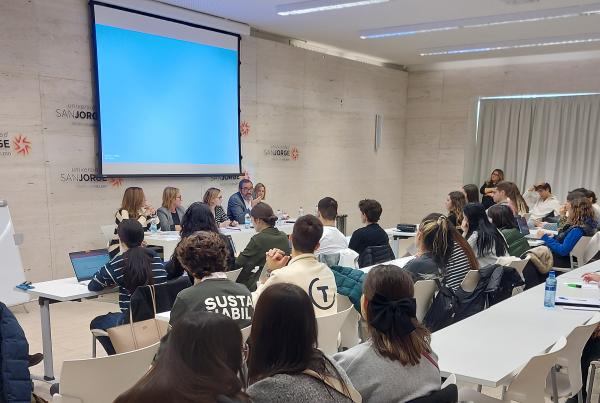 Imagen del aula magna de la universidad san jorge con el alumnado de espaldas en primer plano y los especialistas al fondo