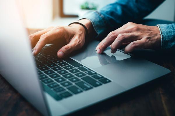 Un portátil con las manos de una persona que lo maneja