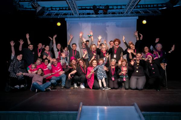 La imagen muestra a parte del equipo de Voluntariado de Fundación Dfa sobre el escenario del salón de actos del Centro de Convivencia para Mayores Laín Entralgo