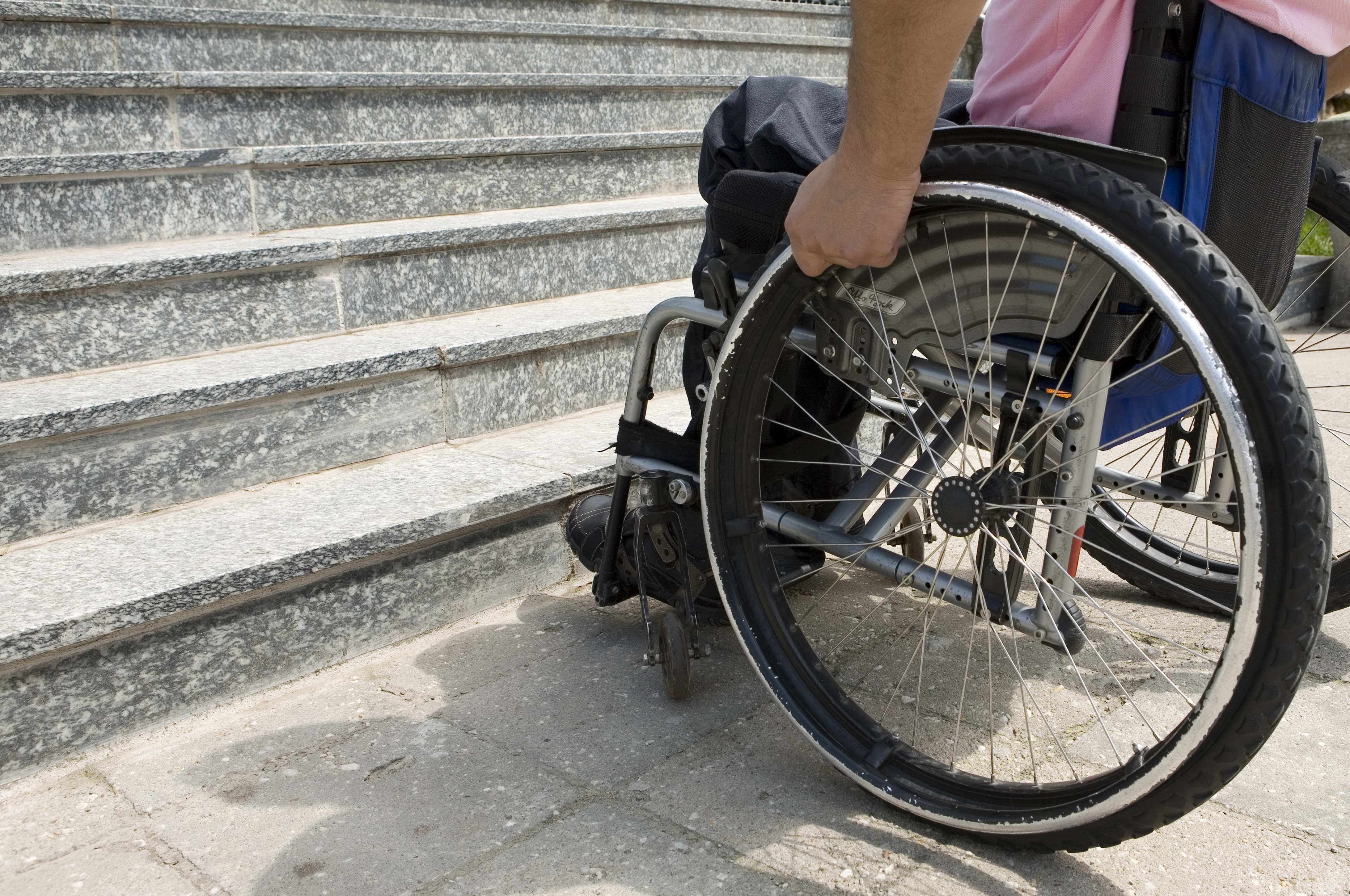 Hombre con discapacidad física en silla de ruedas delante de unas escaleras